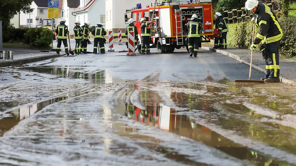 Einsatzkraefte-der-Feuerwehr-reinigen-eine-ueberflutete-und-verschmutzte-Strasse