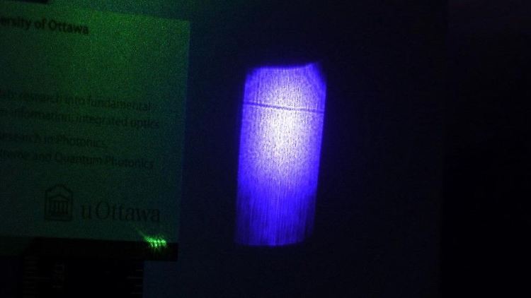 Der feine dunkle Strich auf dem blau angestrahlten Kristallblock ist der von einem Laserstrahl erzeugte Schatten.