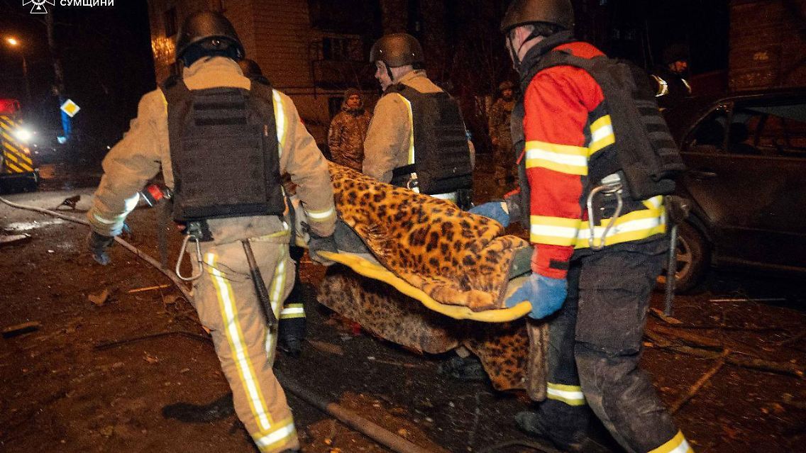 Rettungskräfte tragen eine verletzte Person zu einem Krankenwagen.