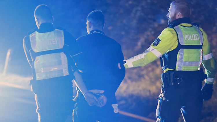 Polizisten führen den LKW-Fahrer ab.