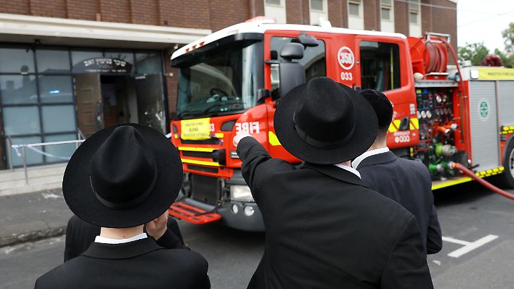 Gemeindemitglieder stehen vor der Synagoge. Ein Mensch erleidet Brandverletzungen. 