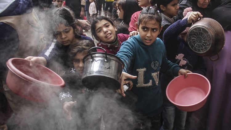 Vertriebene Palästinenser, darunter Kinder, warten, um Mahlzeiten zu erhalten, die von Wohltätigkeitsorganisationen in einem Lager in Gaza-Stadt verteilt werden. 