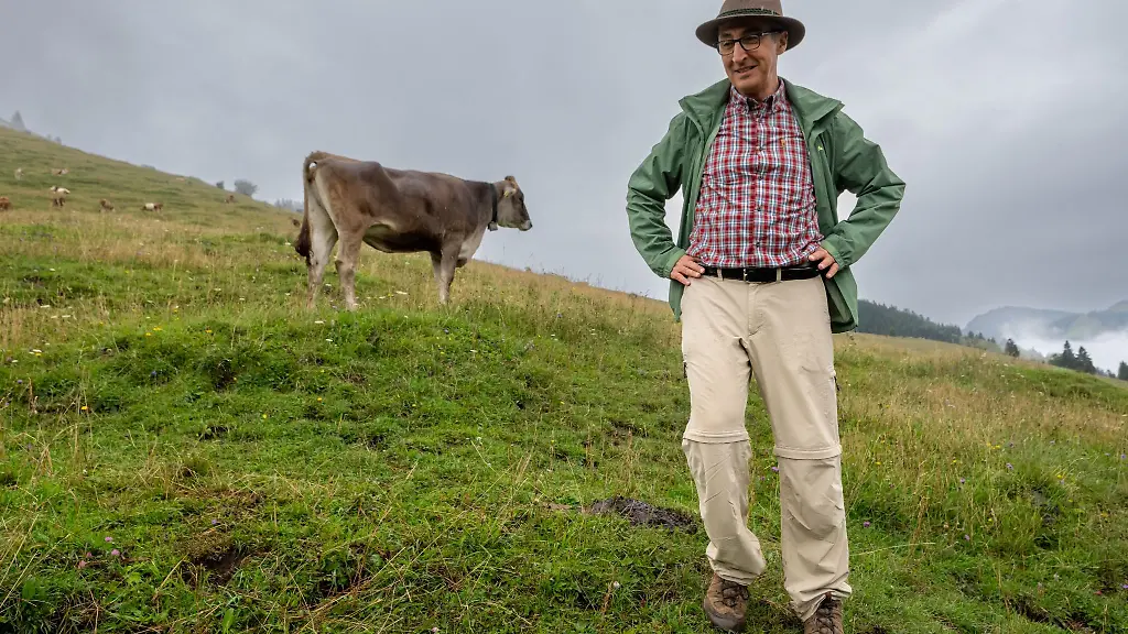 Bundeslandwirtschaftsminister-Cem-Oezdemir-steht-waehrend-der-Hauptalmbegehung-auf-einer-Kuhwiese