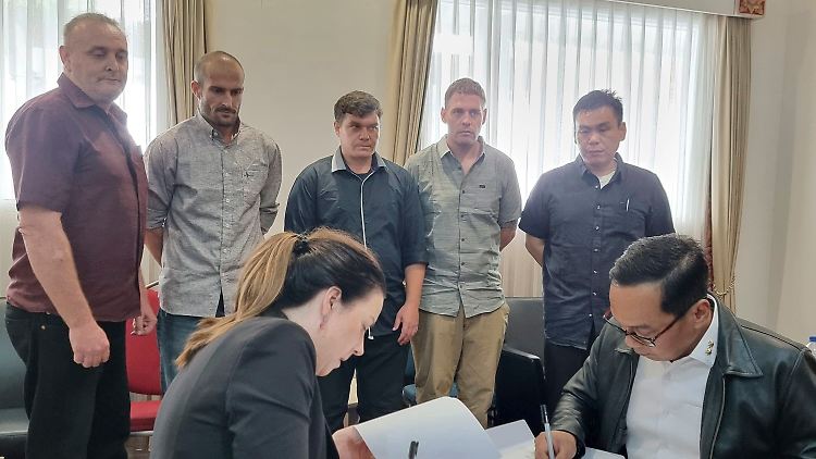 Indonesische und australische Beamte unterzeichnen die Dokumente für die Inhaftierten vor der Übergabe.