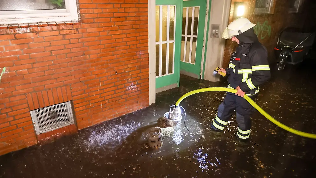 Einsatzkraefte-der-Feuerwehr-pumpen-Regenwasser-aus-einem-Keller-auf-die-Strasse