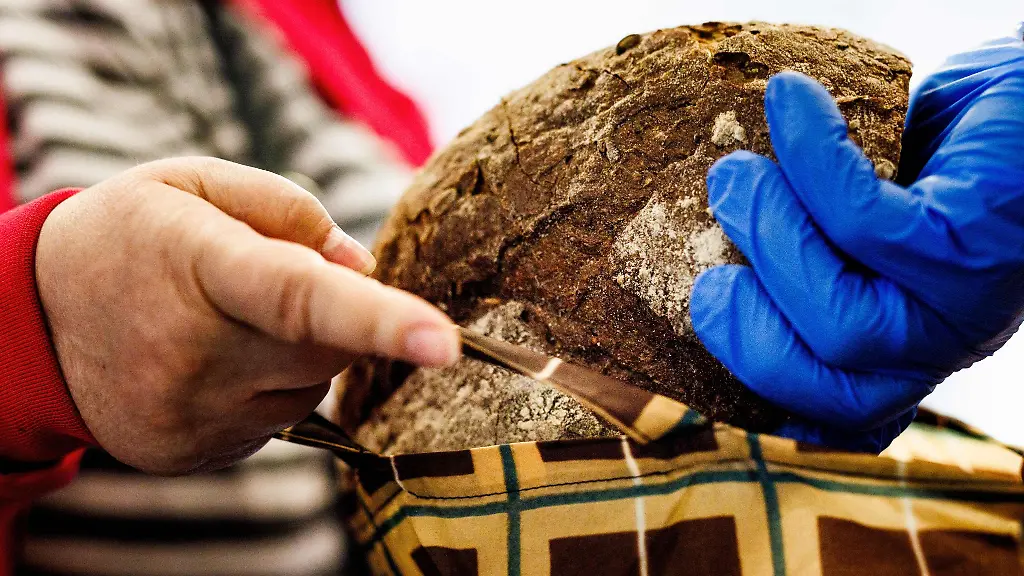 Ein-Mitarbeiter-gibt-ein-Brot-in-die-Tasche-einer-Frau