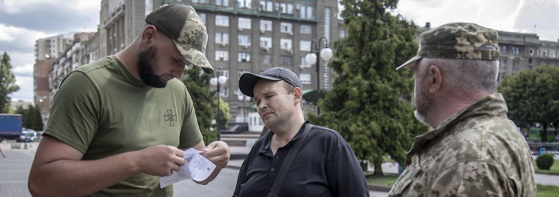 Mitglieder des Rekrutierungsbüro in Charkiw überprüfen die Papiere eines Zivilisten. Sie suchen Männer im kampffähigen Alter, die einberufen werden können.