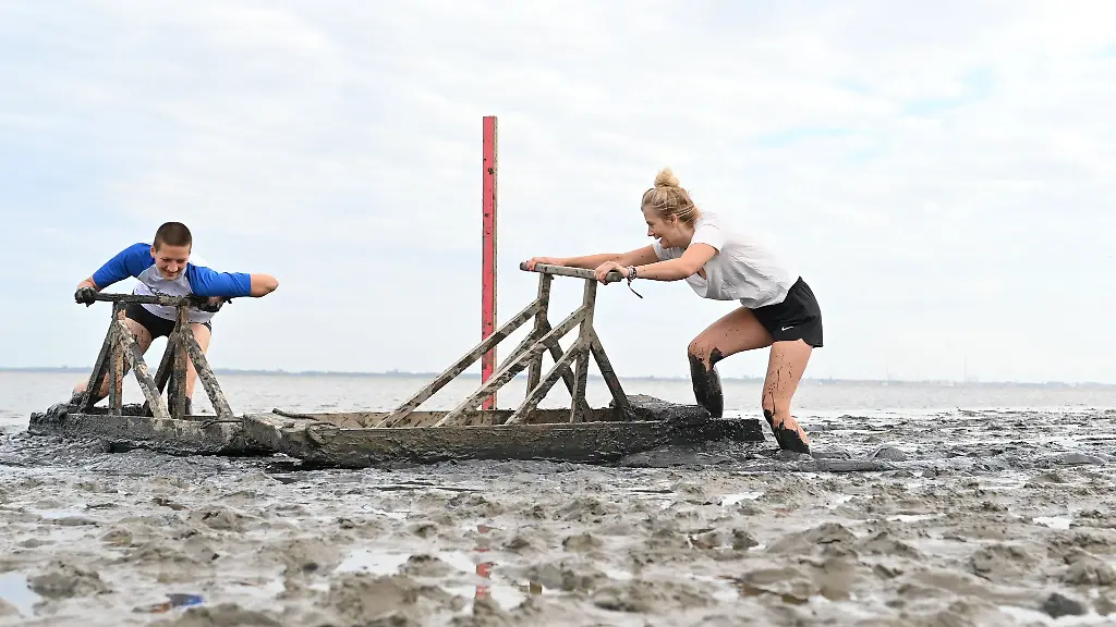 Teilnehmerinnen-der-diesjaehrigen-Deutschen-Meisterschaft-im-Schlickrutschen-rutschen-am-Kurhausstrand-in-Dangast-durchs-Watt