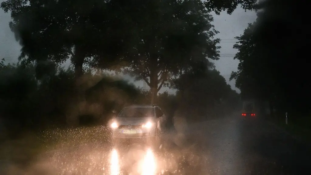 Ein-Auto-faehrt-waehrend-eine-Unwetters-bei-Starkregen-ueber-eine-Strasse