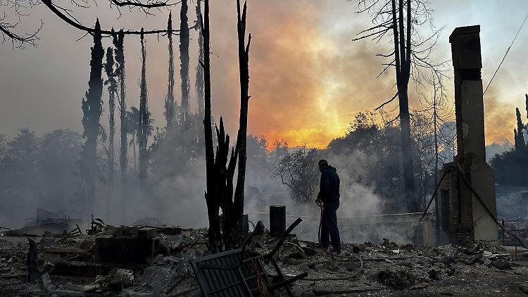 Ein Anwohner spritzt heiße Stellen in einem vom Feuer verwüsteten Haus ab, nachdem das Palisades-Feuer im Stadtteil Pacific Palisades in Los Angeles ausgebrochen ist. 
