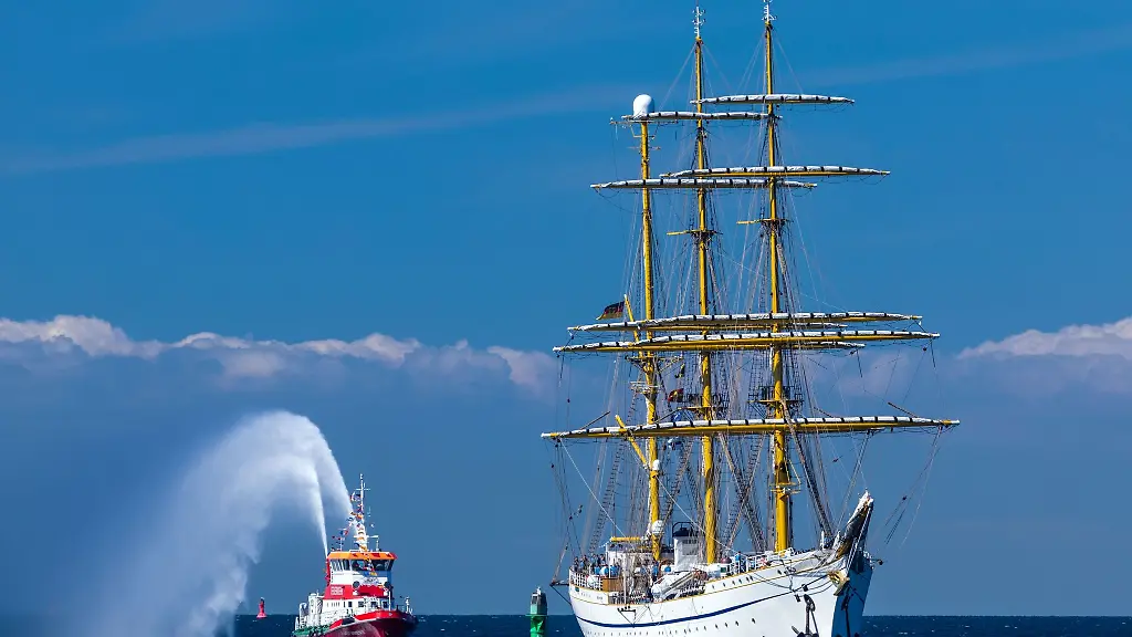 Das-Segelschulschiff-der-Deutschen-Marine-die-Gorch-Fock-steuert-2022-den-Hafen-von-Rostock-an-und-wird-vom-Feuerloeschboot-begruesst