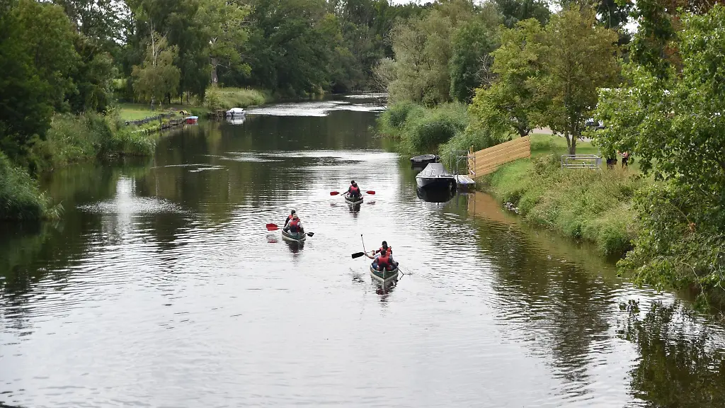 Wassersportler-sitzen-in-drei-Kanus-und-fahren-ueber-die-Bode-bei-Nienburg-Saale