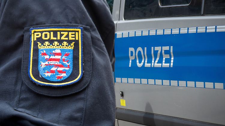 Ein Polizist der hessischen Polizei vor einem Einsatzfahrzeug (Archivbild). 