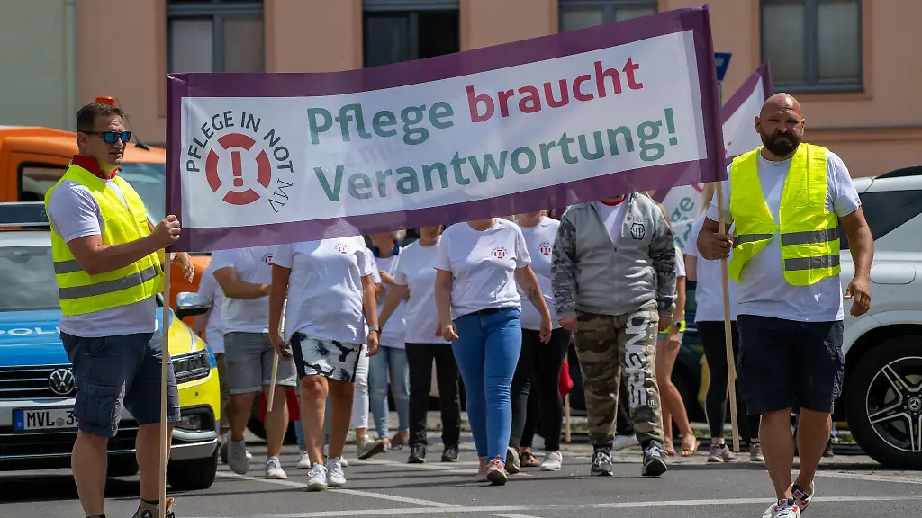 Mitarbeiter-von-Pflegediensten-demonstrieren-mit-Plakaten-fuer-bessere-Arbeitsbedingungen