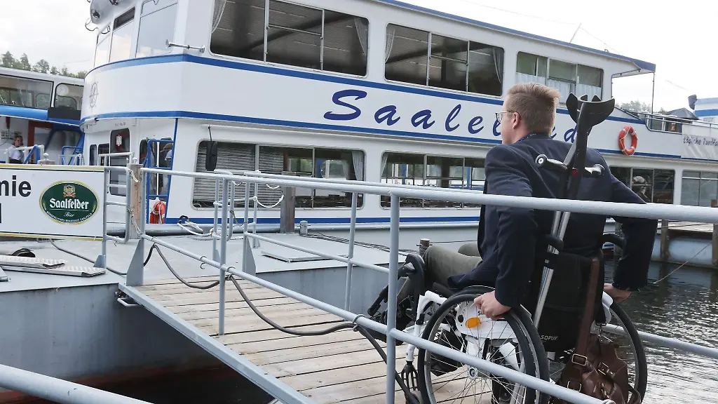 Rollstuhlfahrer-Dennis-Detschner-faehrt-ueber-einen-barrierefreien-Steg-auf-das-Fahrgastschiff-Saaleland-auf-dem-Stausee-Hohenwarte