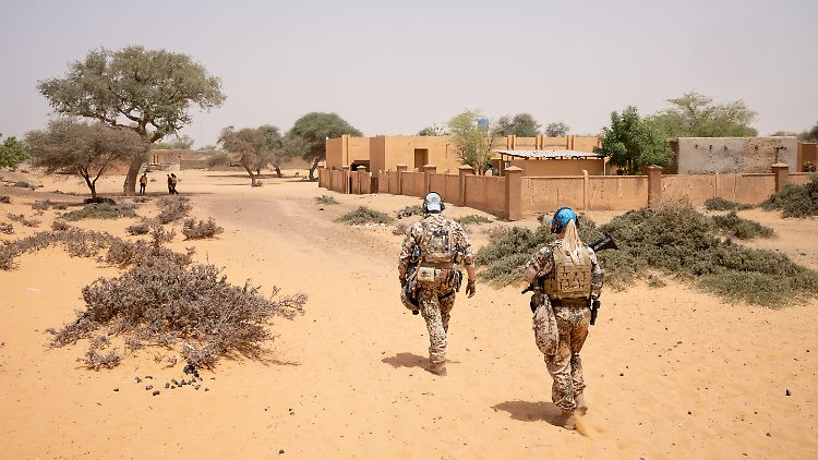Ein Soldat und eine Soldatin der Bundeswehr marschieren auf einer Patrouille durch den Norden Malis. 