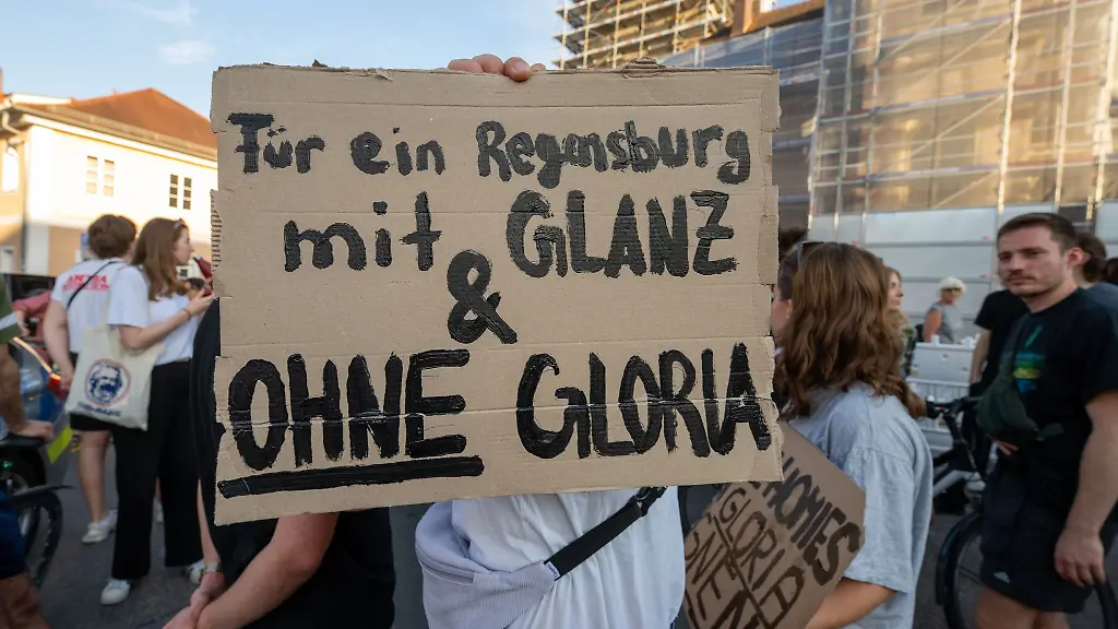 Ein-Schild-wird-waehrend-einer-Demonstration-vor-dem-Fuerstenschloss-St-Emmeram-in-die-Hoehe-gehalten