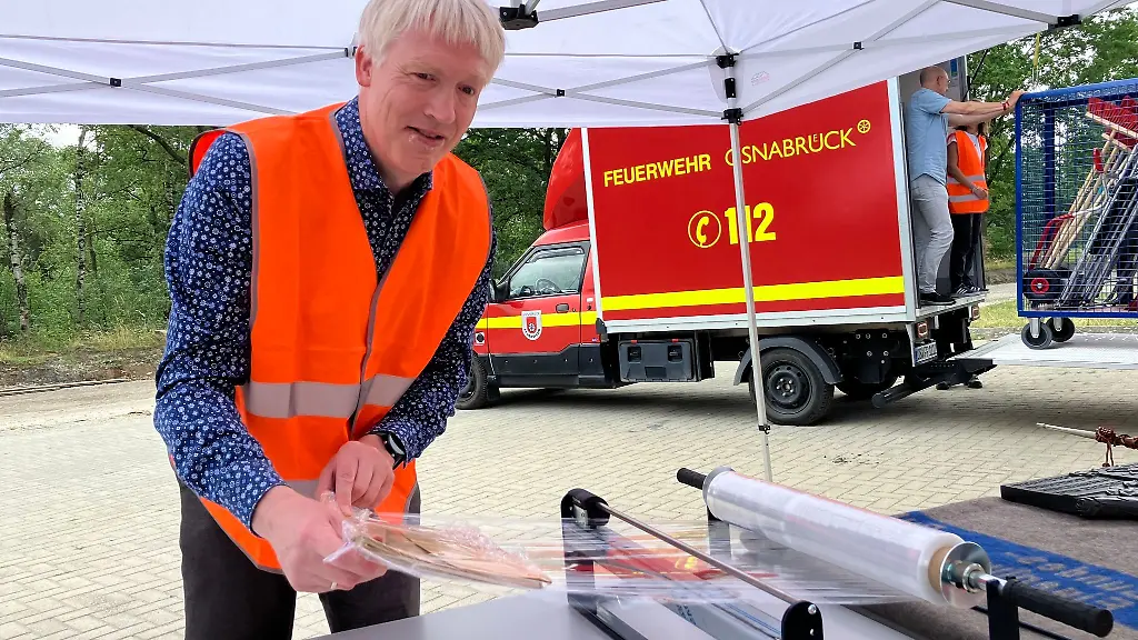 Thomas-Brakmann-vom-Landesarchiv-Osnabrueck-wickelt-einen-Aktenordner-in-Schutzfolie-ein