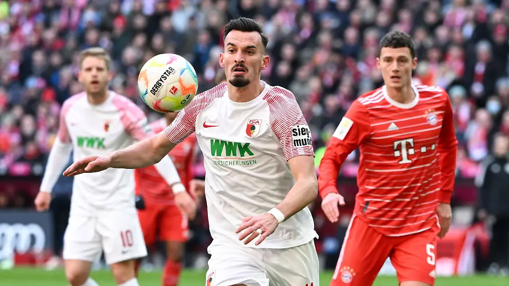 Benjamin-Pavard-r-von-Muenchen-und-Mergim-Berisha-von-Augsburg-kaempfen-um-den-Ball