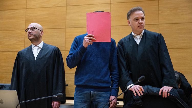 Einer der Angeklagten (M.) steht zwischen seinen beiden Anwälten beim Beginn des Prozesses am Landgericht  Bielefeld.  