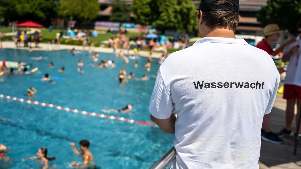 Ein-Mann-von-der-Wasserwacht-steht-waehrend-der-Auftaktveranstaltung-zur-Kampagne-Bayern-schwimmt-2023-oberhalb-den-Schwimmbecken