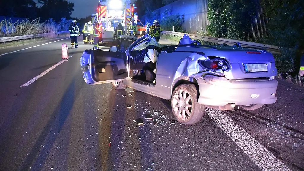 Das-zerstoerte-Fahrzeug-steht-nach-dem-Unfall-auf-der-Autobahn-A57-im-Hintergrund-arbeiten-Rettungskraefte