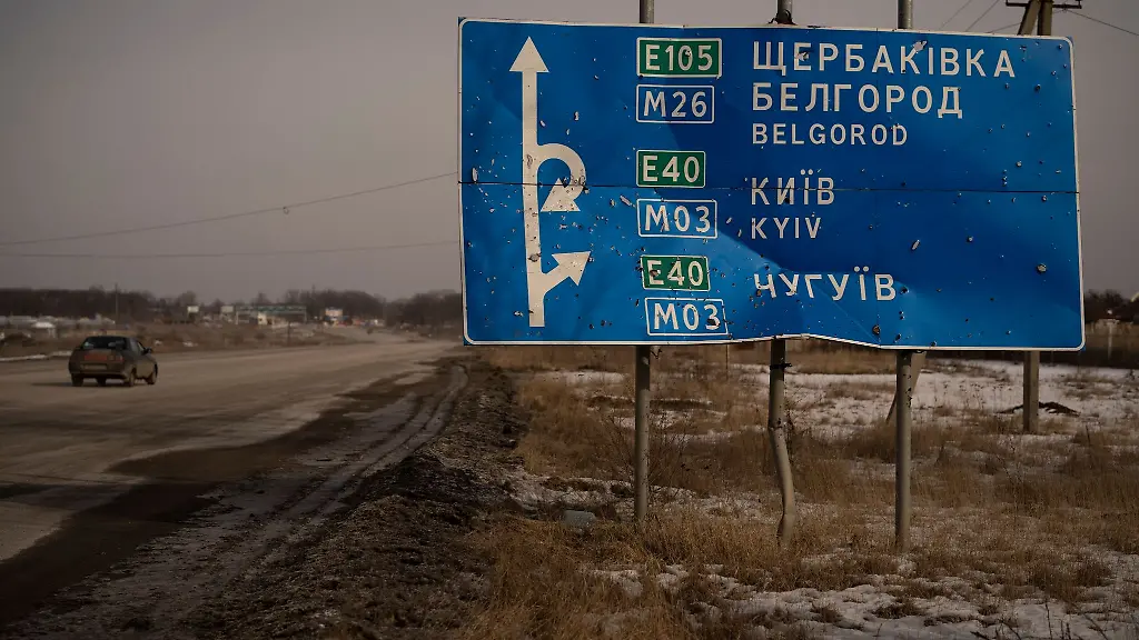 Ein-Auto-faehrt-an-einem-von-Kugeln-und-Granatsplittern-beschaedigten-Strassenschild-auf-der-Strasse-zur-russischen-Stadt-Belgorod-vorbei