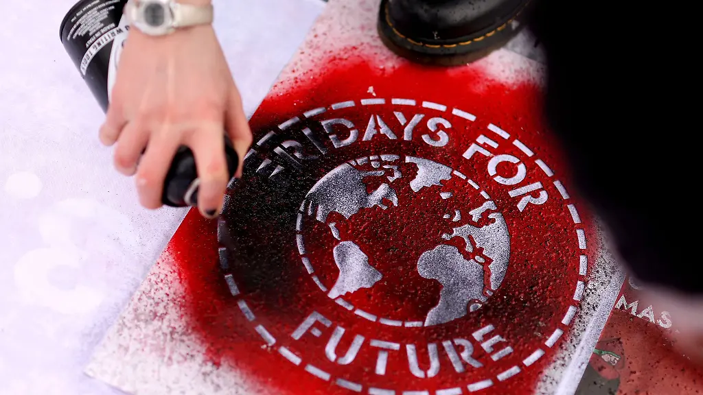 Eine-Klimaaktivistin-sprueht-ein-Fridays-For-Future-Logo-auf-ein-Transparent
