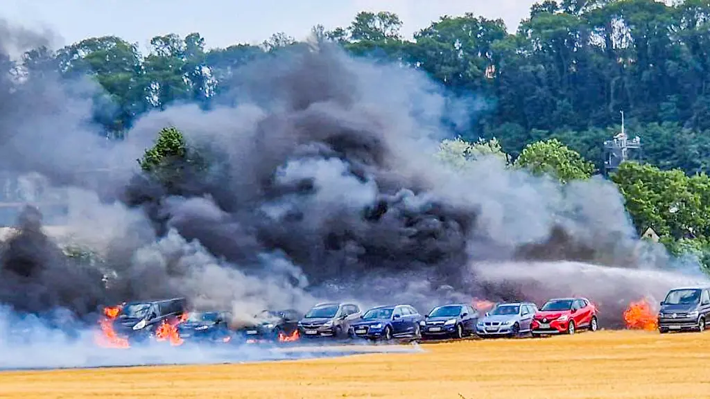 Einsatzkraefte-der-Feuerwehr-loeschen-auf-einem-Behelfsparkplatz-ein-Feuer