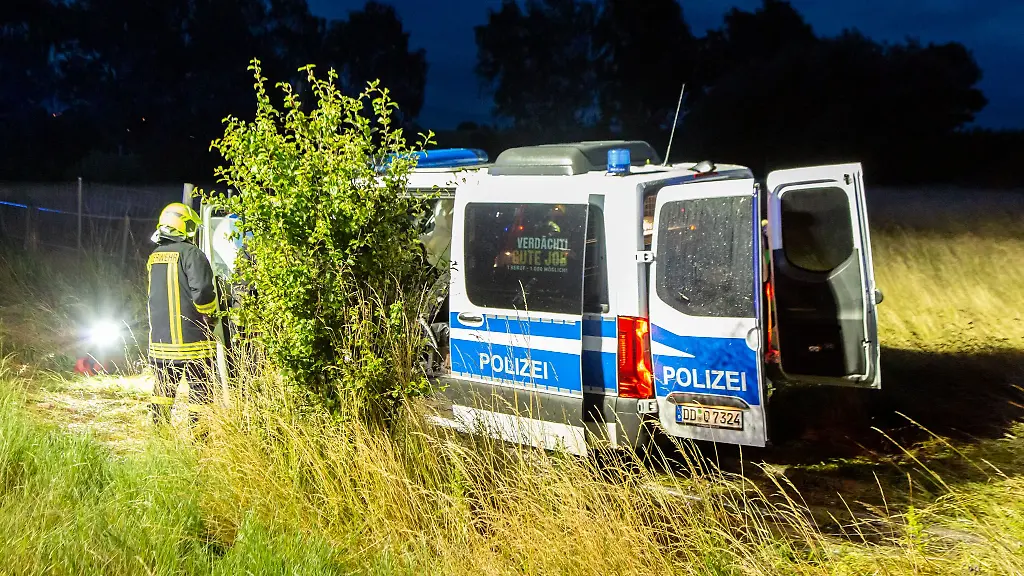 Ein-Mannschaftswagen-der-Polizei-steht-in-einem-Grasfeld