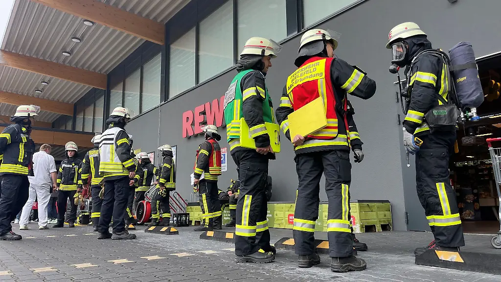 Feuerwehrleute-stehen-von-einem-Supermarkt-18-Menschen-sind-in-Bielefeld-am-Samstagmorgen-bei-einem-Grosseinsatz-der-Feuerwehr-an-einem-Supermarkt-wegen-Atemwegsreizungen-behandelt-worden