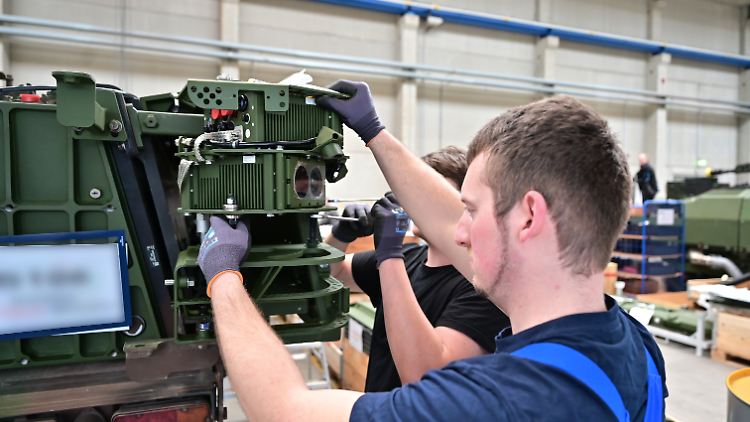Mitarbeiter des Rüstungskonzerns Rheinmetall montieren ein Kamerasystem an einen Panzer.