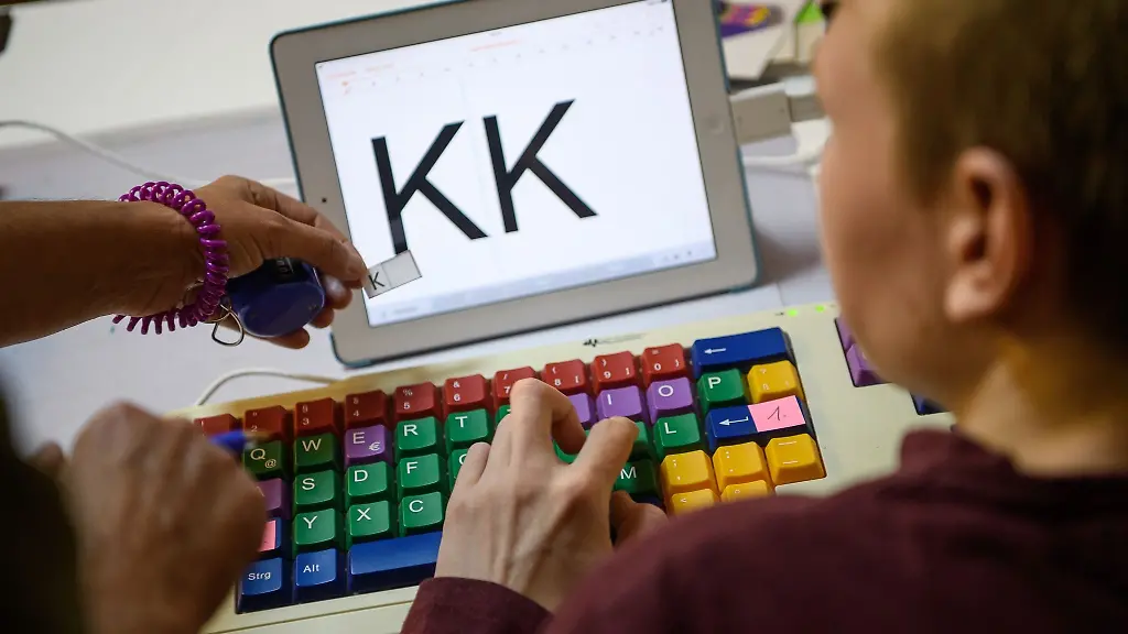 Eine-Therapeutin-uebt-mit-einem-autistischen-Kind-das-Erkennen-und-Schreiben-von-Buchstaben-auf-einer-Tastatur