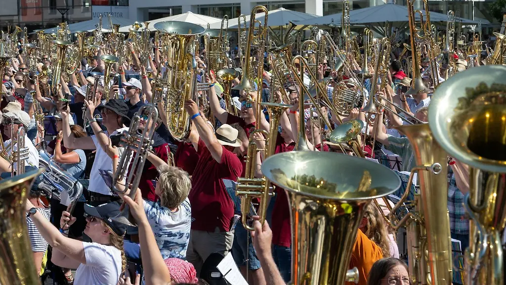 Blasmusiker-heben-auf-dem-Muensterplatz-zur-Begruessung-ihre-Instrumente