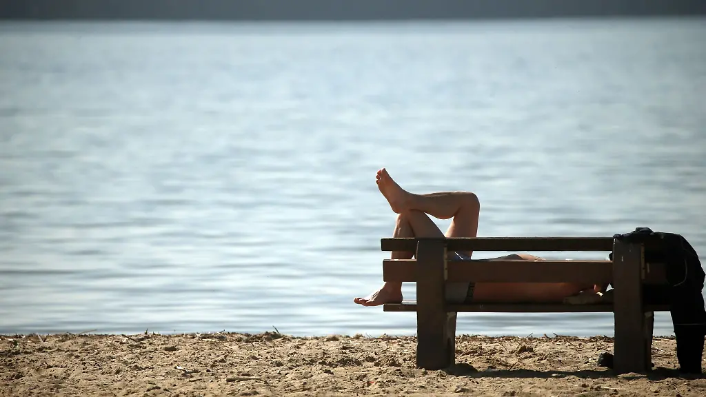 Ein-Mann-liegt-in-einem-Strandbad-auf-einer-Bank