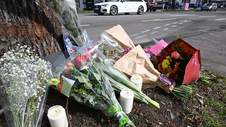 An der Unfallstelle legen Menschen Blumen ab.