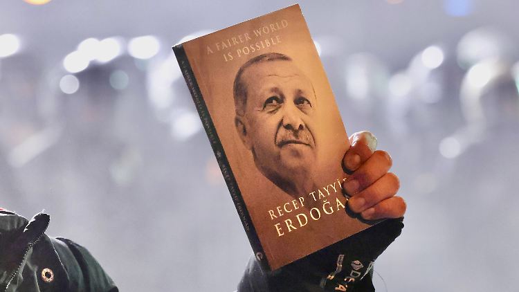 Ein Demonstrant hält der Polizei ein Buch von Erdoğan entgegen: "Eine gerechtere Welt ist möglich".