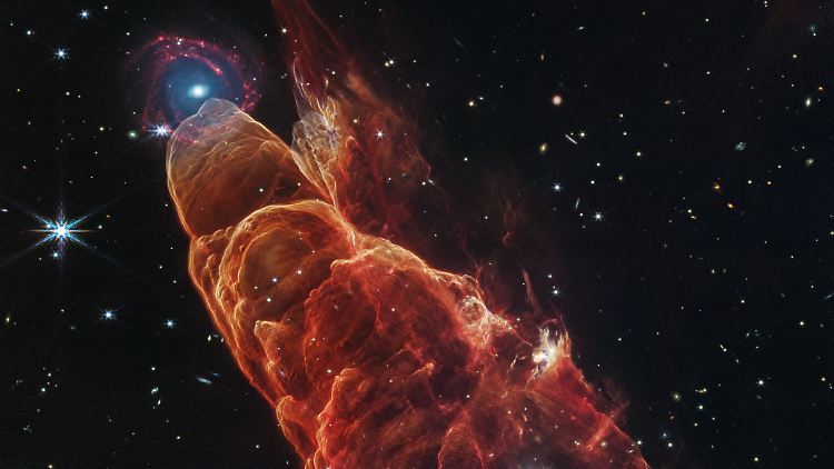 Dieses Bild des NASA-Weltraumteleskops "James Webb" zeigt den Ausfluss eines nahen, sich noch bildenden Sterns im Infrarotlicht, mit einer Spiralgalaxie in der Ferne.