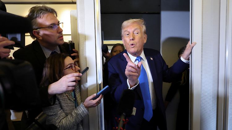 Trump spricht an Bord der Air Force One vor Journalisten.