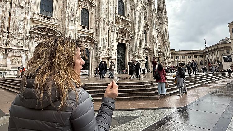 Eine Touristin steht mit einer Zigarette vor dem Mailänder Dom.