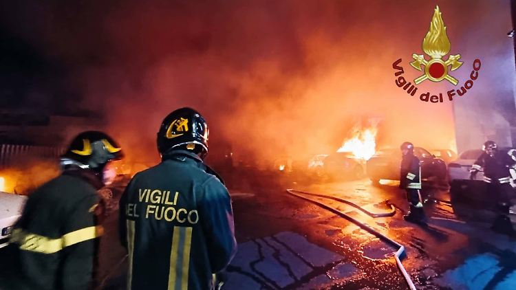 Feuerwehrleute beim Löschen des Brandes die auf einem Parkplatz eines Tesla-Händlers in Rom.