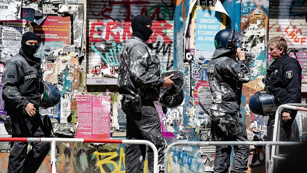 Mit-Farbe-beworfene-Polizeibeamte-verlassen-ein-Haus-in-der-Rigaer-Strasse