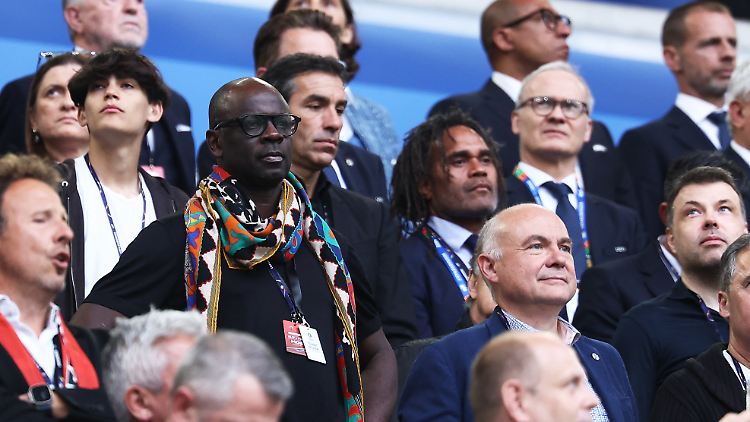 Liliam Thuram (mit buntem Schal) besucht ein Spiel der EM 2024 - neben ihm steht sein früherer Nationalmannschaftskollege Christian Karembeu (mit Dreadlocks).
