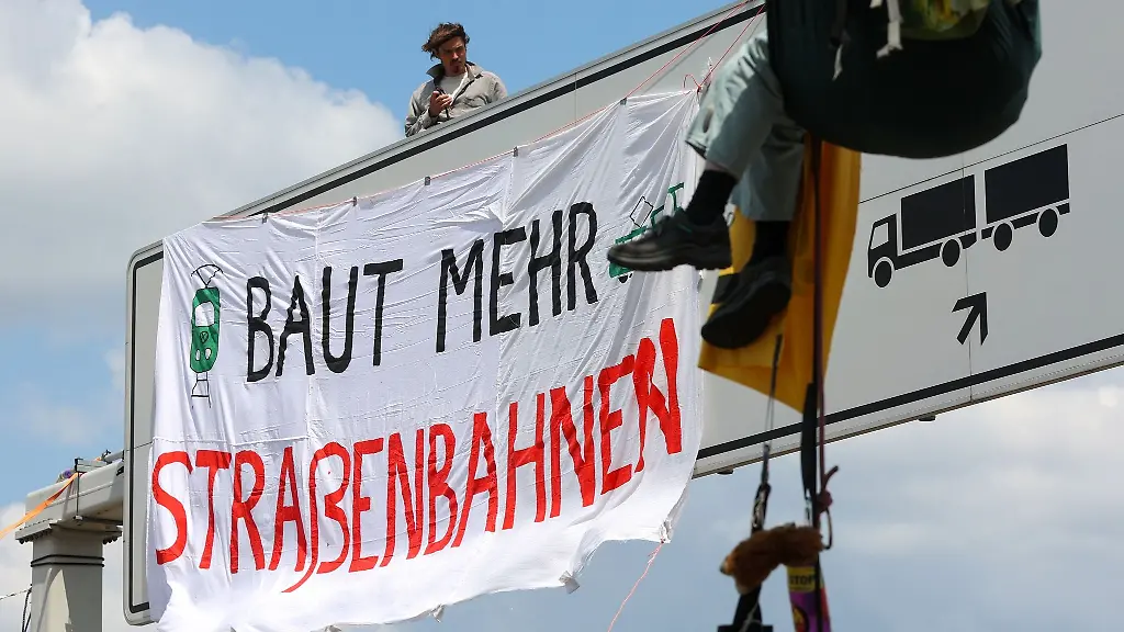 Aktivisten-befestigen-ein-Transparent-an-einer-Schilderbruecke