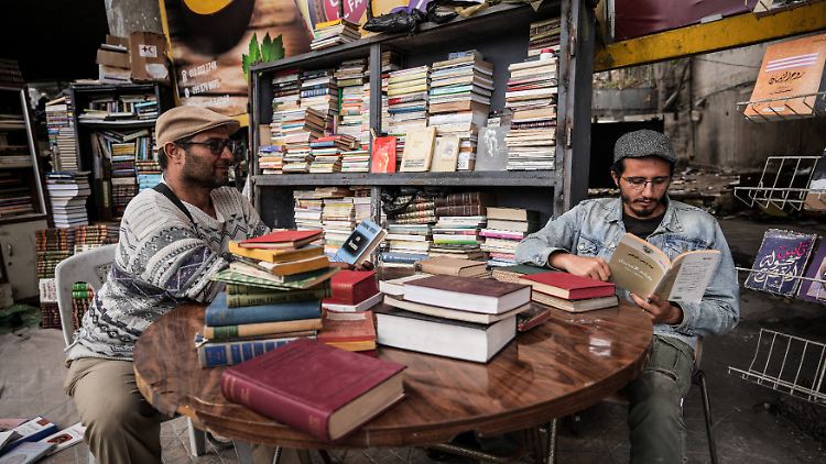 Die syrischen Buchhändler Adallah Hamdan (l.), der religiöse Bücher verkauft, und Adham Ajamja, der politische Bücher verkauft, stöbern auf dem Freiluftbüchermarkt in Damaskus.