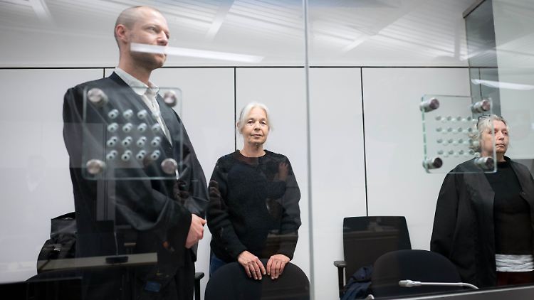 Daniela Klette steht mit ihren Anwälten im Gerichtssaal hinter Panzerglas. 
