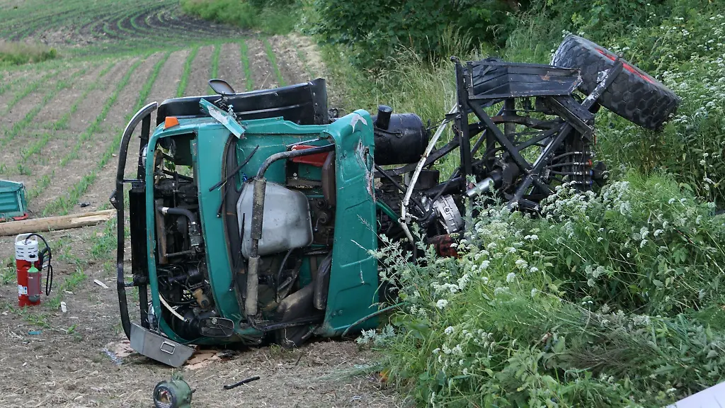 Ein-zerstoerter-Unimog-liegt-auf-einem-Feld-neben-einem-Bahnuebergang