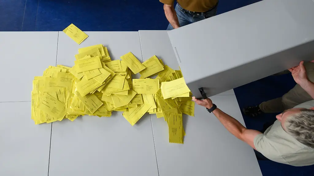 Stimmzettelumschlaege-fuer-eine-Briefwahl-werden-aus-einer-Wahlurne-geschuettet