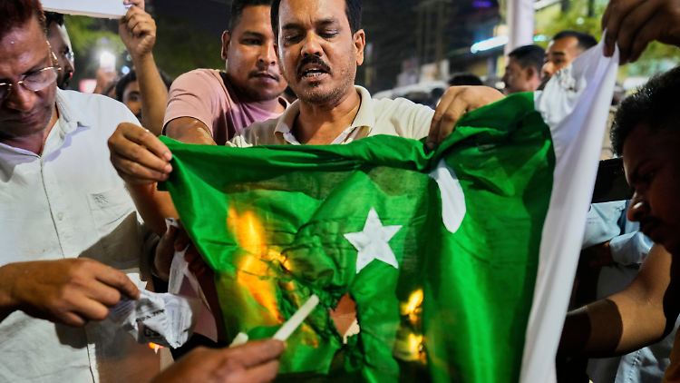 Demonstranten in Kaschmir verbrennen die pakistanische Flagge. 