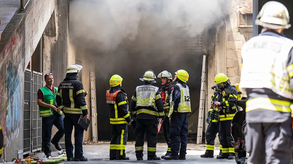 Einsatzkraefte-der-Feuerwehr-loeschen-den-Vollbrand-eines-Lagers